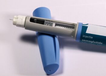 Injectiepen voor een afslankmedicijn op een tafel naast een bord met groente