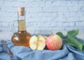 Fles appelazijn naast een glas water op een aanrecht