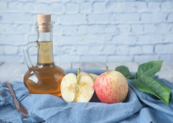 Fles appelazijn naast een glas water op een aanrecht