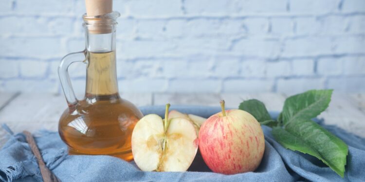 Fles appelazijn naast een glas water op een aanrecht