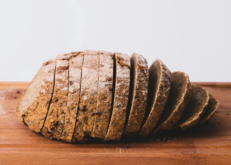 Sneetjes volkorenbrood naast een kom havermout op een houten plank