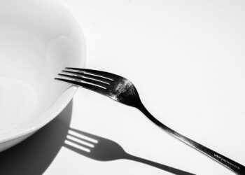 Kom gekookte pasta met een vork op een houten tafel