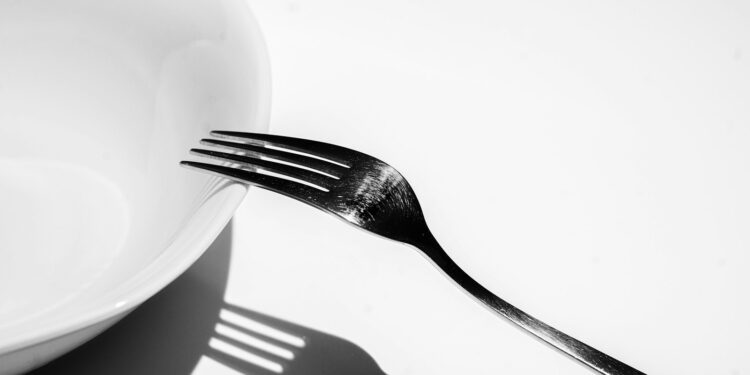 Kom gekookte pasta met een vork op een houten tafel