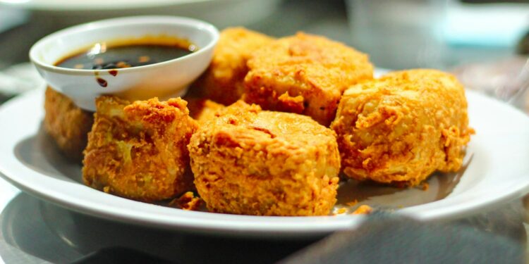 Blokken tofu, tempeh en een glas sojadrink op een keukentafel