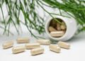 Potje met vitamine D-capsules naast een glas water op tafel
