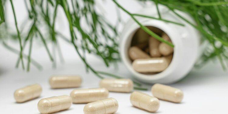 Potje met vitamine D-capsules naast een glas water op tafel