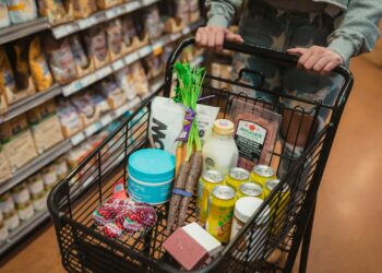 Boodschappenmandje met groente, brood en zuivel in een supermarktgangpad