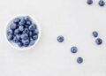 Kom yoghurt met verse blauwe bessen op een keukentafel
