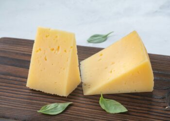 Glas melk en een stuk kaas op een houten tafel