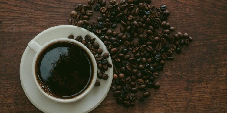 Kop zwarte koffie met koffiebonen op tafel