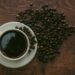 Kop zwarte koffie met koffiebonen op tafel