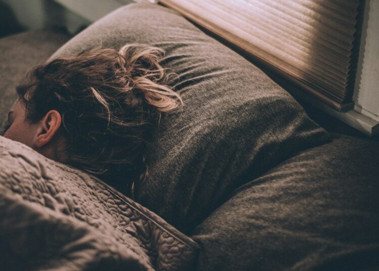 Vrouw ligt diep te slapen in een bed met wit beddengoed