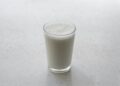 Glas karnemelk en een fles kefir op tafel