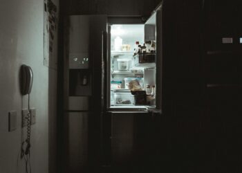 Iemand pakt 's avonds laat iets te eten uit een verlichte koelkast