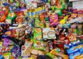 Verpakte snacks en frisdrank naast een bord met verse groente