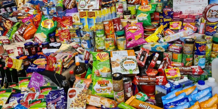 Verpakte snacks en frisdrank naast een bord met verse groente