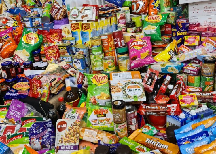 Verpakte snacks en frisdrank naast een bord met verse groente