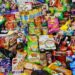 Verpakte snacks en frisdrank naast een bord met verse groente