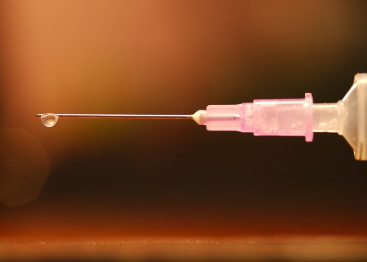 Injectiespuit en klein glazen flesje op een tafel