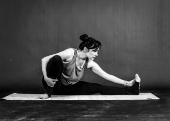 Vrouw van middelbare leeftijd rekt haar been en knie op een yogamat