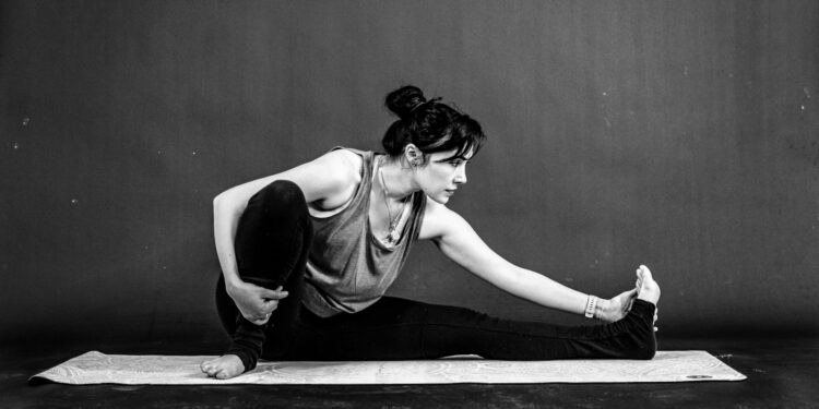 Vrouw van middelbare leeftijd rekt haar been en knie op een yogamat