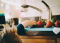 Peuter in een kinderstoel die een stuk fruit eet