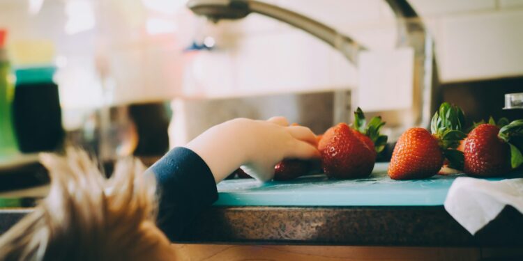 Peuter in een kinderstoel die een stuk fruit eet
