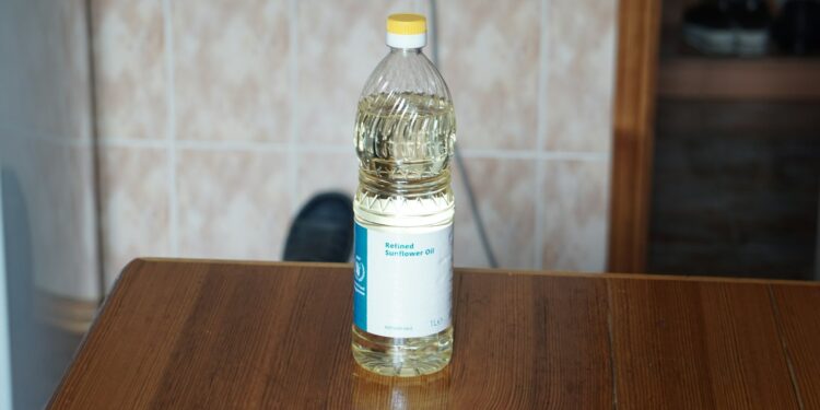 Fles zonnebloemolie naast een koekenpan