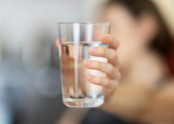 Glas water op een lege tafel als symbool voor vasten