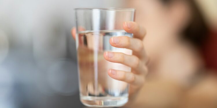 Glas water op een lege tafel als symbool voor vasten